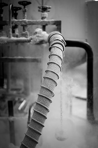 Black and white industrial pipe with frost and steam