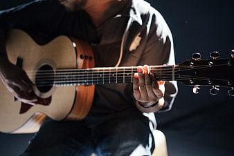 Close-up of man playing acoustic guitar with dramatic lighting