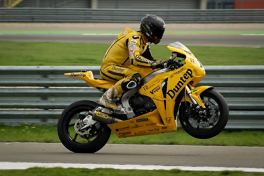 Yellow racing motorcycle performing a wheelie on a race track