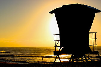 Silhouette of Lifeguard Tower at Golden Sunset on Beach