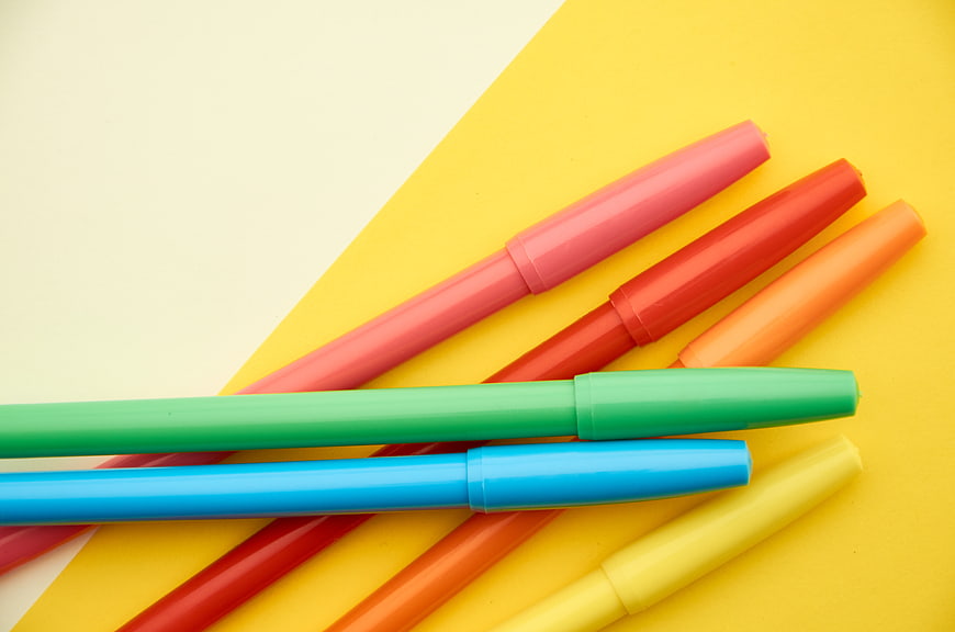 Colorful markers on yellow and white background