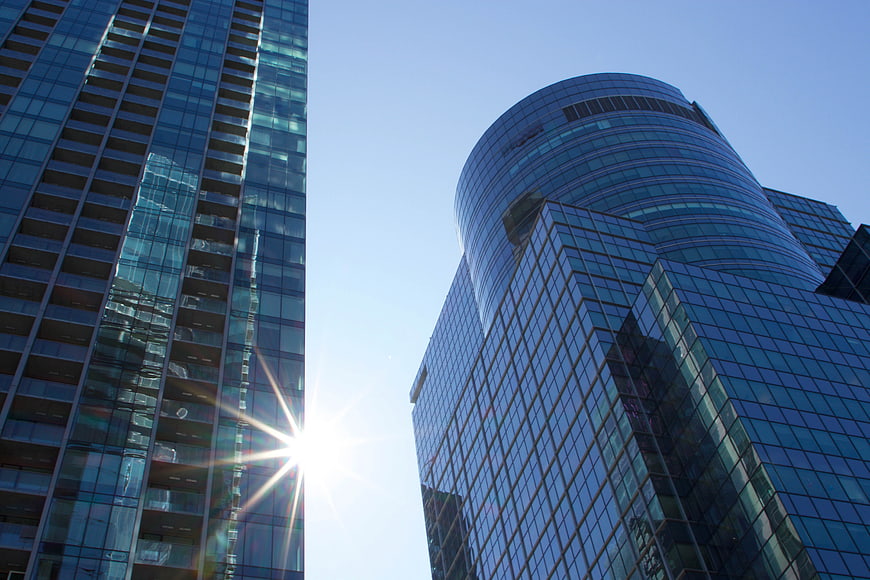 Modern Glass Skyscrapers with Sun Flare and Blue Sky