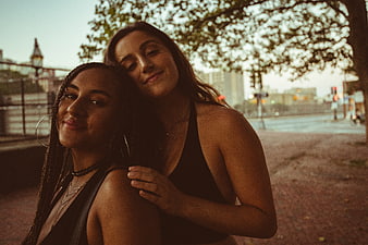 Two smiling women embracing on a city street at sunset