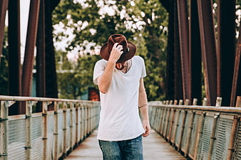 Man in Fedora Hat Walking on Bridge