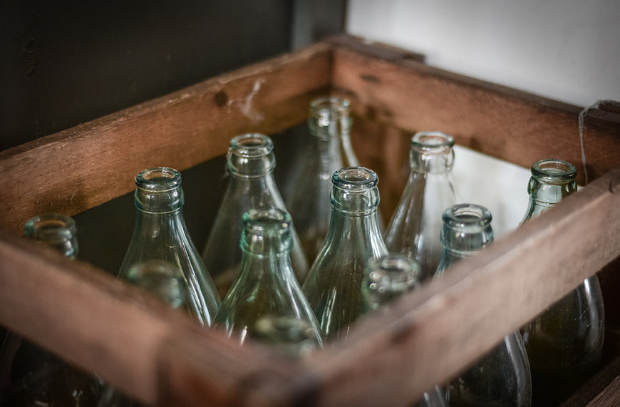 Vintage green glass bottles in a rustic wooden crate