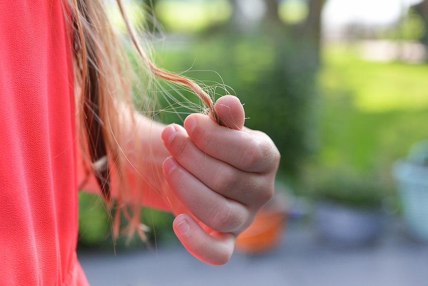 Close-up of child's hand holding tangled hair outdoors