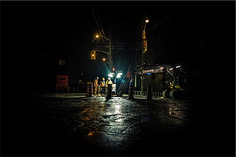 Construction workers and excavator at night on wet street