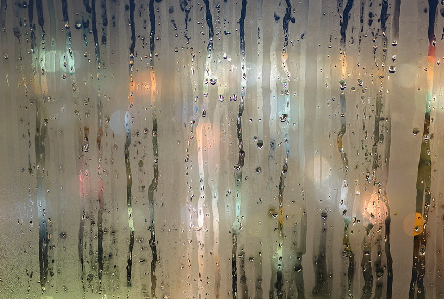 Raindrops on Window with Blurred City Lights Background