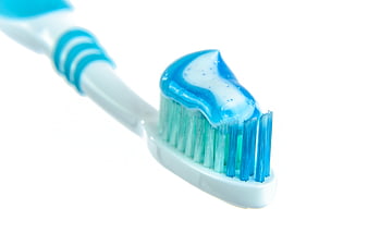 Close-up of blue toothbrush with gel toothpaste on white background