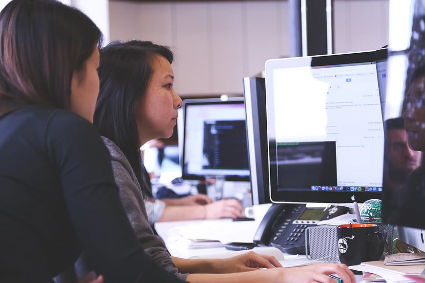 Two Women Working at Computer Monitors in Office