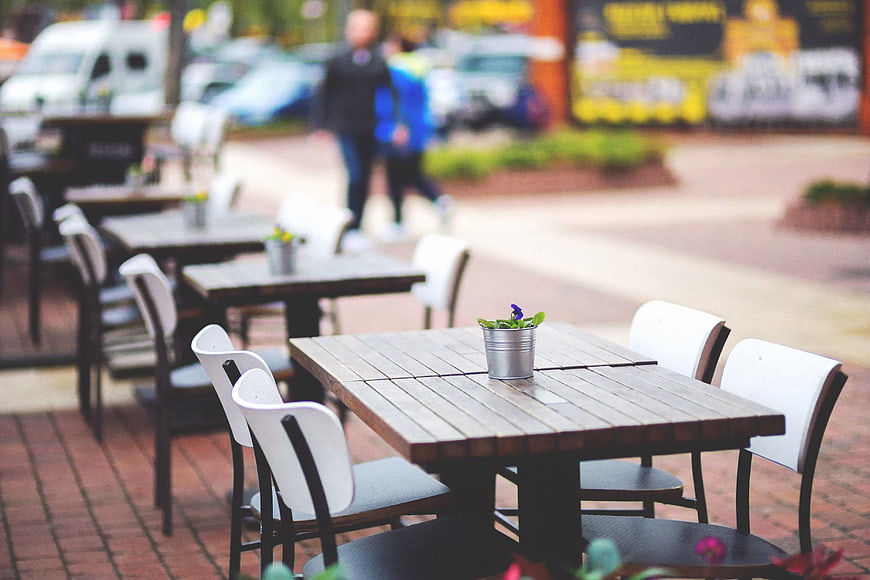 Empty outdoor cafe terrace with wooden tables and chairs