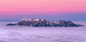 Snowy Mountain Peak Rising Above Sea of Clouds at Pink Sunset