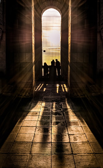 Sunbeams streaming through arched window onto stone floor