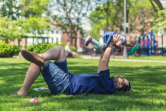 Father lifting baby in park on sunny day