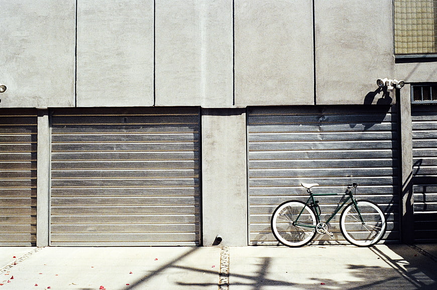 Green Bicycle Parked Against Concrete Garage Doors