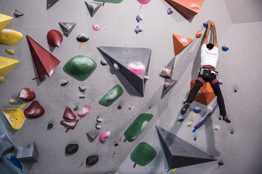 Man climbing indoor rock wall with colorful holds