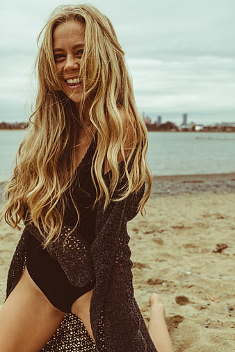 Happy Blonde Woman in Black Swimsuit on Sandy Beach