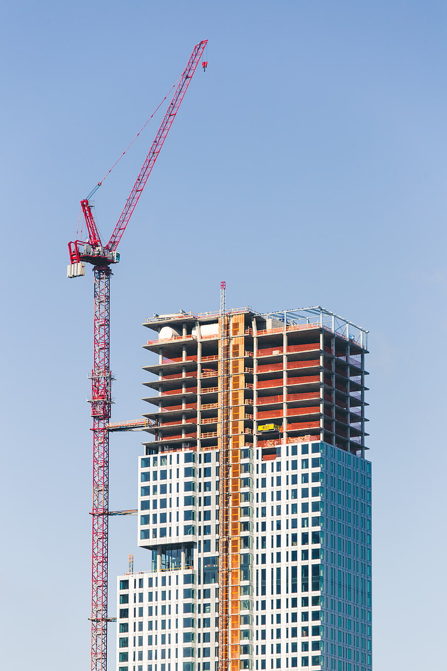Red Construction Crane Next to High-Rise Building Under Construction