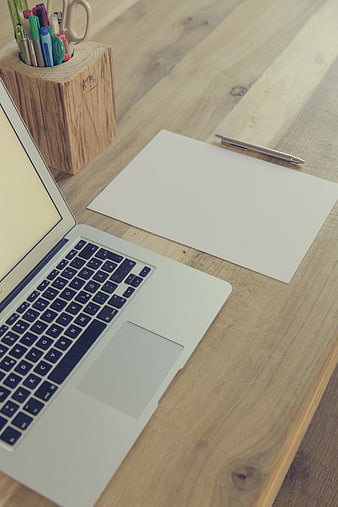 Minimalist wooden workspace with laptop and blank paper