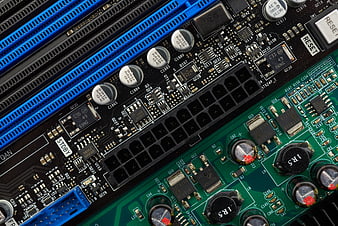Close-up of computer motherboard with blue RAM slots and green circuit board