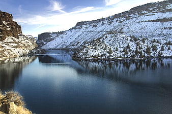 Serene Winter River Valley with Snow-Covered Cliffs and Reflections