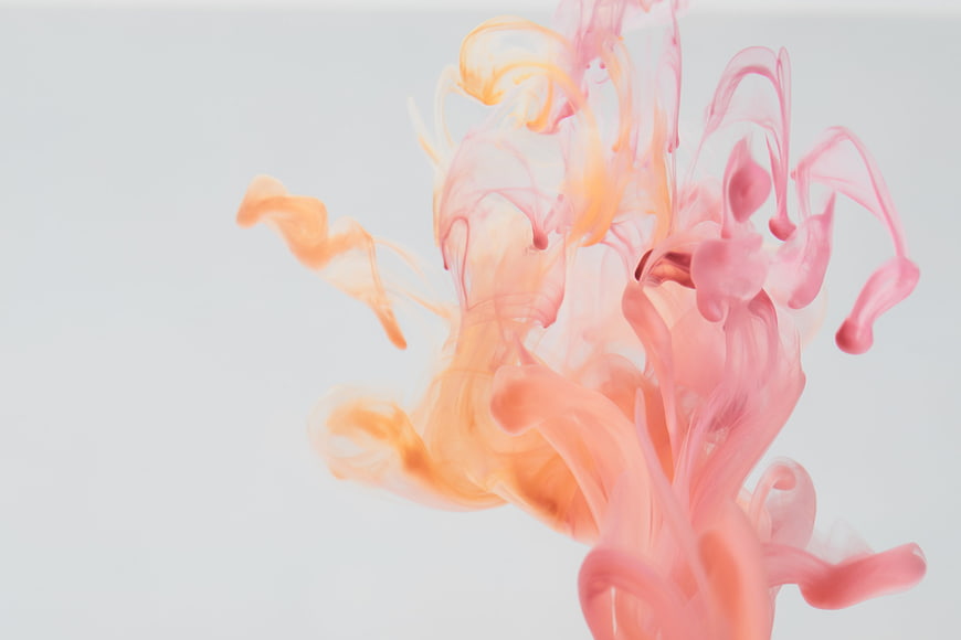 Abstract pink and orange ink swirling in water