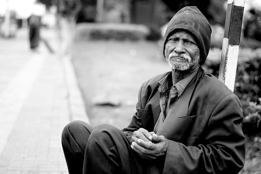 Senior man sitting on street curb in black and white