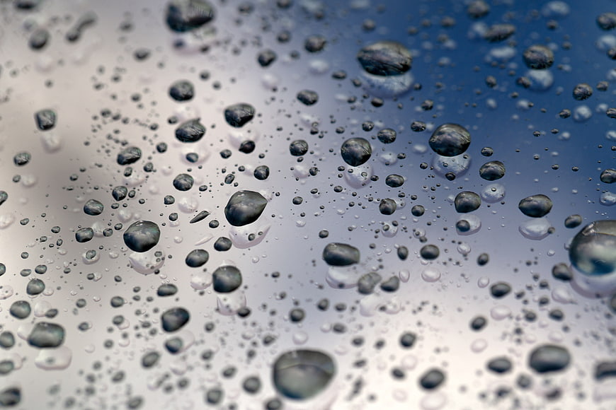 Macro water droplets on glass with blue and white gradient background