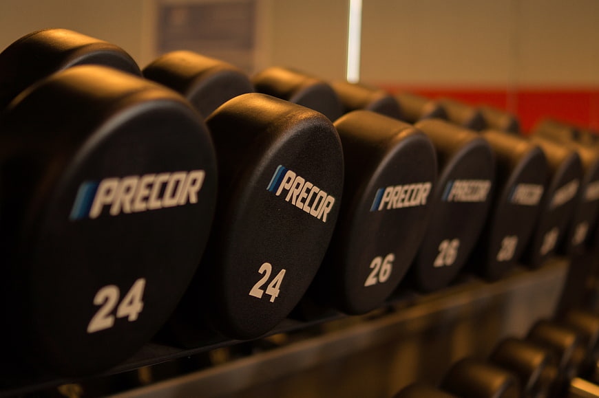 Row of black Precor dumbbells on gym rack