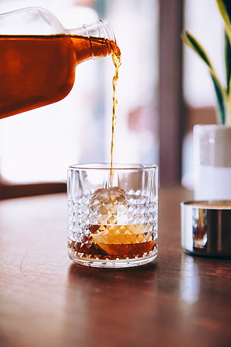 Pouring Amber Whiskey into Crystal Glass with Ice