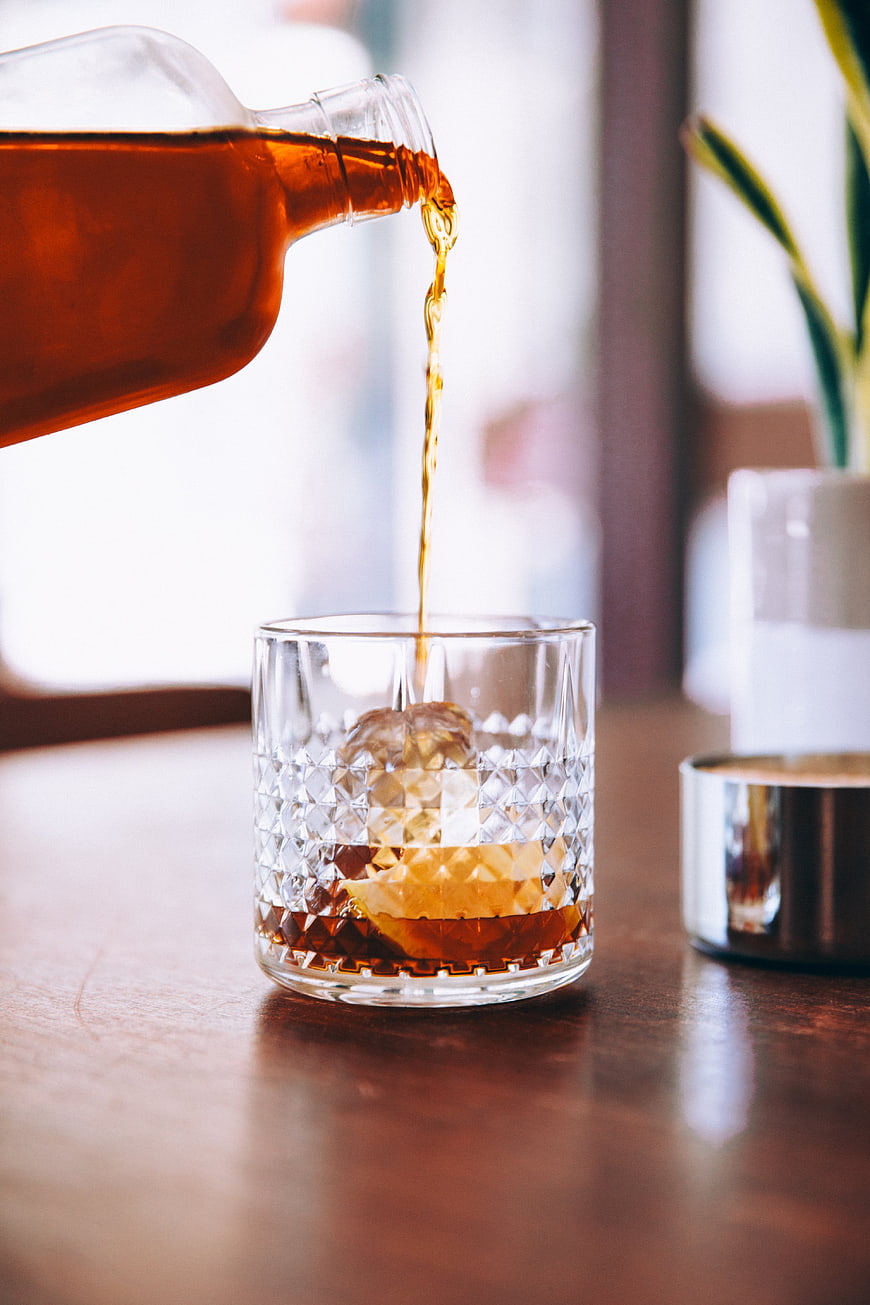 Pouring Amber Whiskey into Crystal Glass with Ice