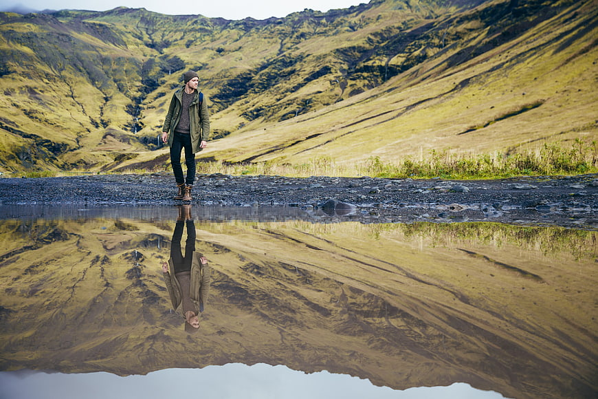 Hiker standing by mountain reflection in valley