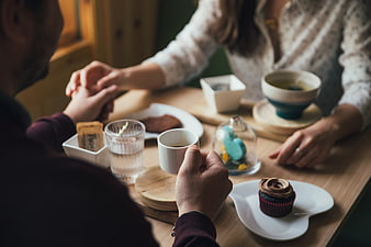 Couple holding hands over coffee and cupcakes at cafe