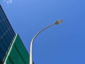 Solar street lamp against blue sky with modern building