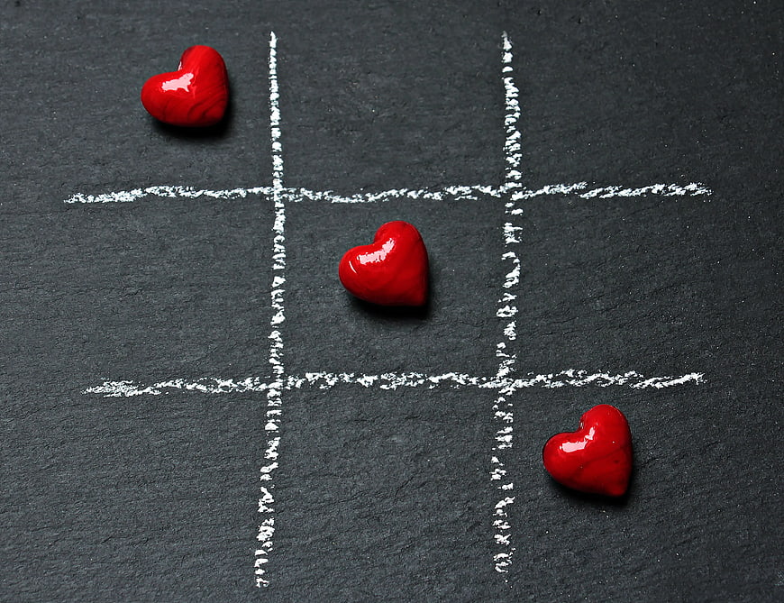 Red hearts playing tic-tac-toe on black slate