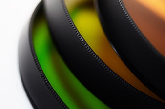 Close-up of stacked camera lens filters with green and orange glass