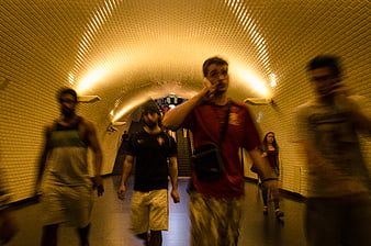 Motion blur of people walking in a tiled subway tunnel