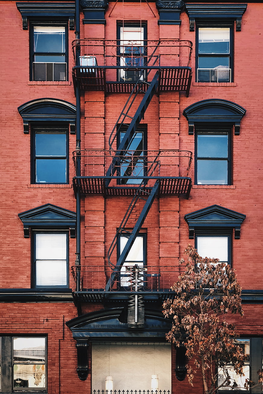 Red brick building facade with black fire escape stairs