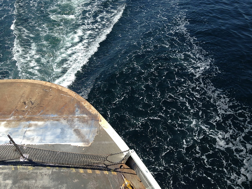 High angle view of rusty ship bow cutting through deep blue ocean waves