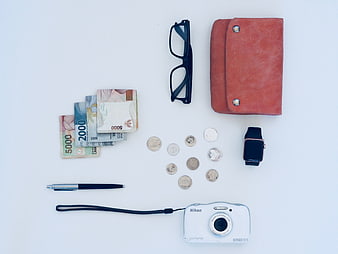 Flat lay of daily essentials including camera, wallet, and cash