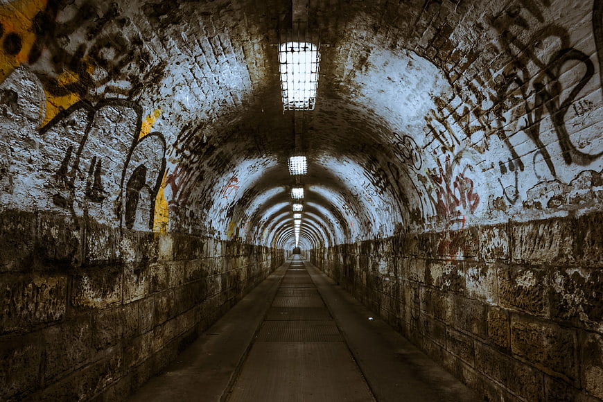Graffiti Covered Arched Tunnel With Overhead Lights