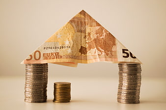 Euro banknote house roof on stacks of coins