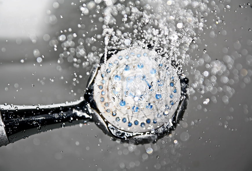 Close-up of black shower head spraying water droplets