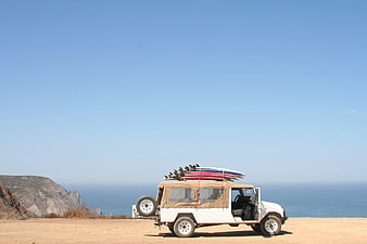 White SUV with Surfboards Parked on Coastal Cliff