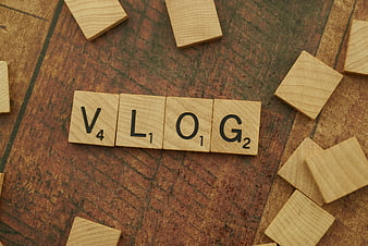 Vlog spelled with wooden Scrabble tiles on rustic background