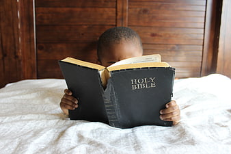 Child Reading Holy Bible in Bed