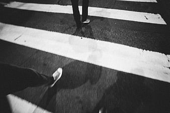 Black and white night photo of feet crossing a street
