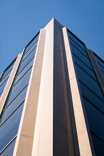 Low angle view of modern office building corner against blue sky