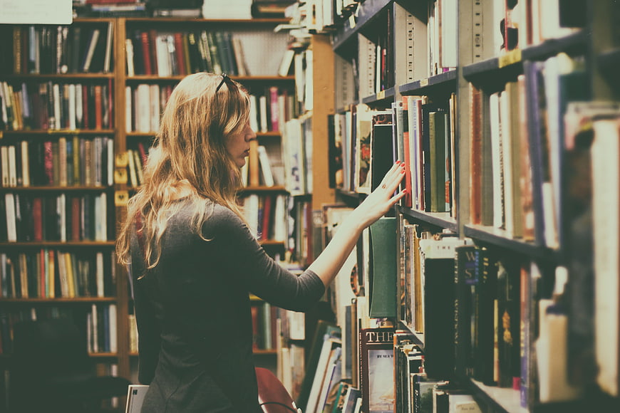Woman browsing books in a vintage bookstore aisle