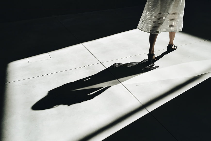 Woman's shadow cast by sunlight on tiled floor